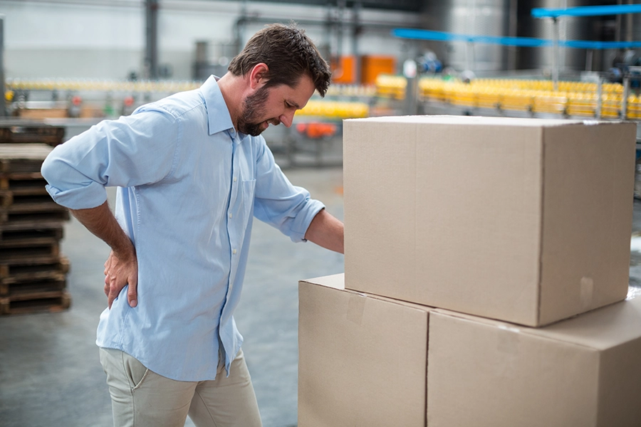 man-in-pain-holding-his-back-in-warehouse_900x600